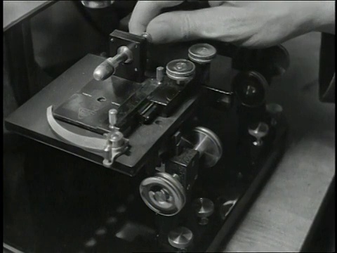 1930年代B/W男子将子弹放在机器上进行显微镜检查视频下载