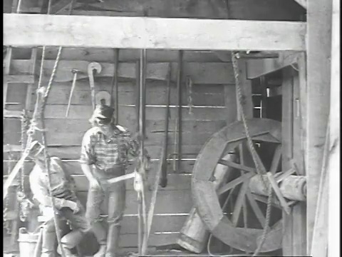 1923年再现:男人四处走动，转弯并将非机械化的石油钻机泵入地面视频素材