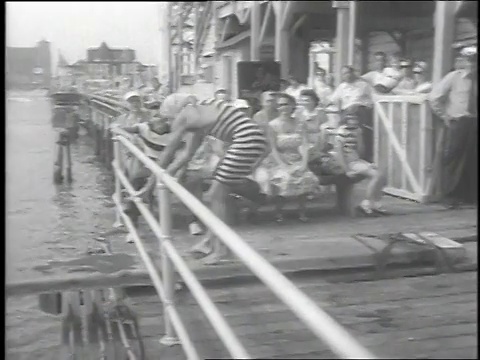 1951年，美国新泽西州大西洋城，滑稽潜水学校，小丑们在跳水板上玩耍的蒙太奇慢动作镜头视频下载