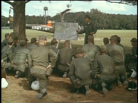 1967年，蒙太奇士兵盯着记事本看，许多直升机紧挨着低飞到地面/美国肯塔基州坎贝尔堡视频下载
