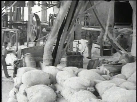 1921蒙太奇在一家石棉产品工厂内，有一个人监控大控制板和破碎和开放的房间，在那里一个人正在把石棉装入破碎机/沃基根，伊利诺伊州，美国视频素材