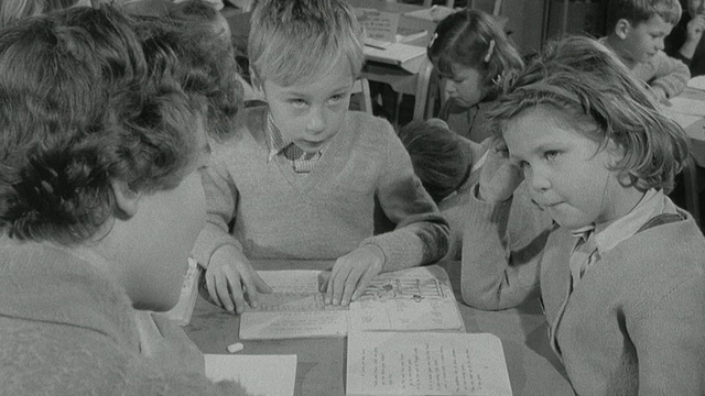 1960蒙太奇儿童在教室里玩游戏和阅读卡片/英国视频素材