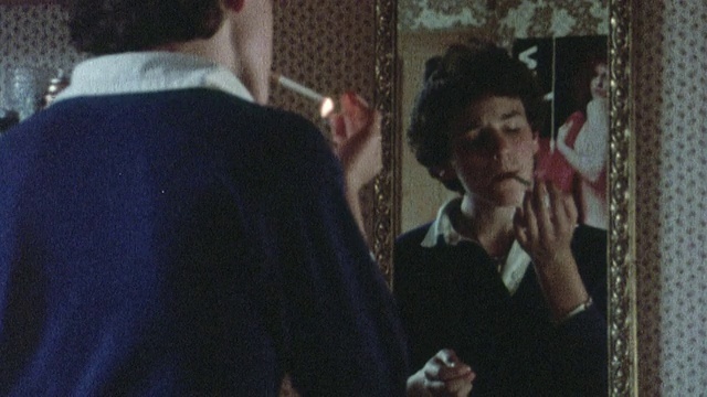1978年，年轻的吸烟者看着镜子中的自己，点上一支烟，抽着，试图看起来很酷/英国视频下载