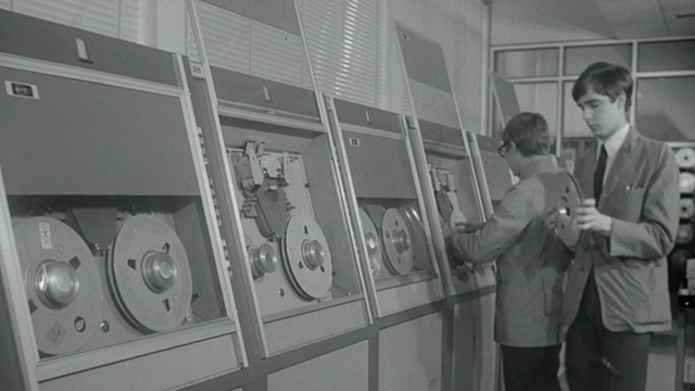 1969蒙太奇计算机技术人员加载数据磁带和穿孔卡到主机/联合王国视频下载