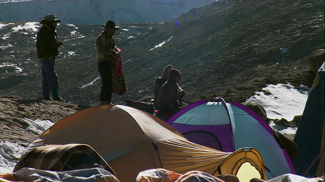 WS地质研究人员站在积雪覆盖的山顶上的帐篷外/美国视频素材