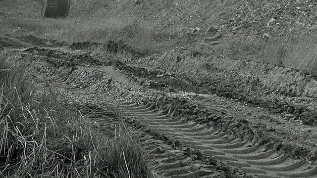 1954年，蒙太奇福登自卸卡车载着泥土沿着车辙、泥泞的道路前往处置区，旁白描述了卡车的齿轮范围/阿克赖特，英国，英国视频素材