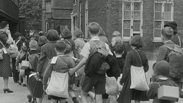 1939年，第二次世界大战/英国期间，孩子们被从城市疏散到乡村，在守卫者的长队中行走，提着包和手提箱视频下载