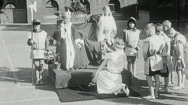 1925年，英国泰恩河畔的加来/纽卡斯尔，蒙太奇学校的学生们穿着当时的服装，在室外表演菲利帕女王请求国王爱德华三世饶了他们一命的历史戏剧场景视频素材