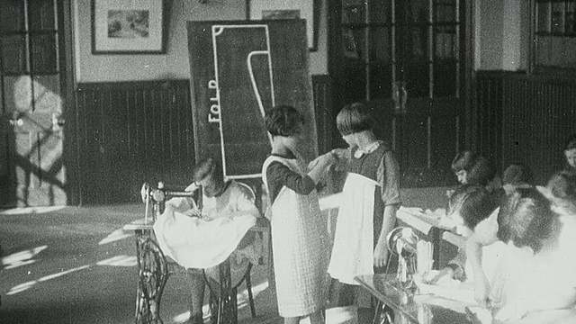 1925年，蒙太奇女学生在家庭经济课上与学生测量同学，学生操作缝纫机，裁剪图案，并拿起成品服装/英国泰恩郡纽卡斯尔视频素材