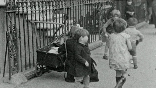 1937蒙太奇贫民区贫民区的门廊、人行道和街道上的母亲和她们的孩子，展示了一些儿童的贫困状况/英国伦敦视频下载