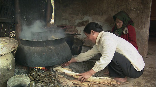 ZI村民在一个大锅下生火，然后把水舀进一个小锅里/越南巴利亚- vung头的巴湾视频下载