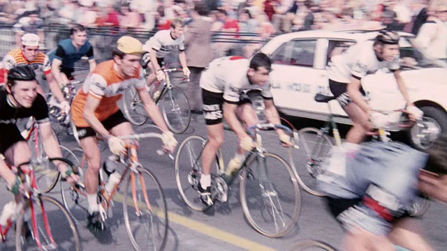 1974蒙太奇骑自行车的人在城市街道上比赛，观众正在观看比赛/英国视频下载