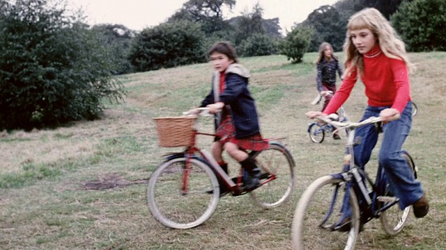 1974蒙太奇儿童骑自行车下山和在开阔的草地上/英国视频下载