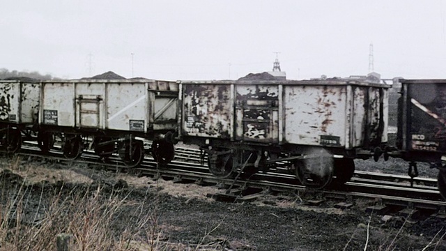 1980年，蒙太奇煤炭列车进入发电站，吹着烟，在铁轨边等待/英国视频素材