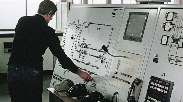 1980 MS电站工作人员面对仪表盘、仪表和监视器面板，并调整控制信号列车/英国视频下载
