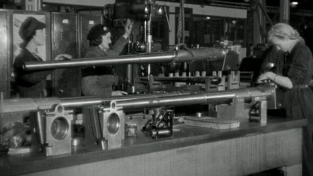 二战军火厂工人通过绞车运送完成的火炮管，其他工人包括那些在办公室观看/英国视频素材