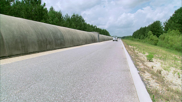 TS货车在一条狭窄的道路上行驶，旁边是一个有盖的混凝土隧道视频下载
