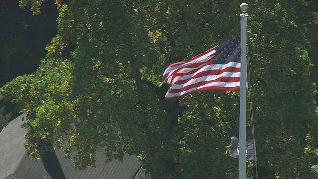 空中飘扬的美国国旗在微风中飘扬，在马萨诸塞州莱克星顿以外的住宅区视频下载
