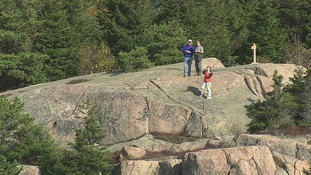 三名游客在崎岖的岩石旋涡上，周围是起伏的山丘和深秋的山谷/缅因州，美国视频下载
