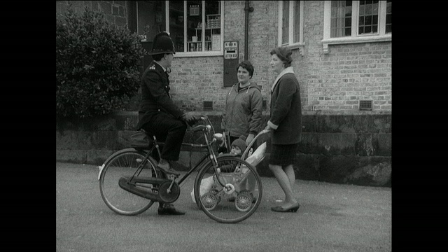 英国切斯特，一辆英国巡逻车停了下来，一名骑自行车的警察在和两名邻居妇女交谈后离开了视频下载