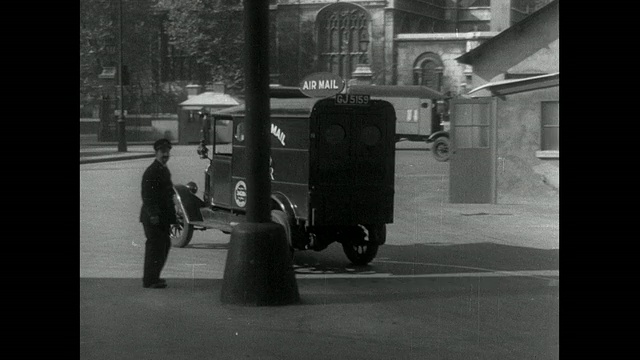 邮政工人称邮袋的重量为空运，并将重量写入分类帐，滴答的钟面，和邮车行驶在城市/伦敦，英国视频下载